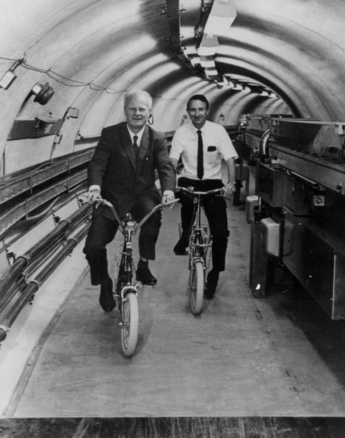 Hans Bethe and Boyce McDaniel ride bicycles in the Cornell Electron Storage Ring
