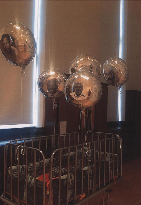 Silver balloons with faces are floating above a crib