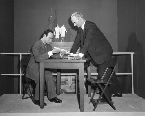 Wax Models of Enrico Fermi and Arthur Compton, with Fermi sitting at a table holding a figure and Compton looking on