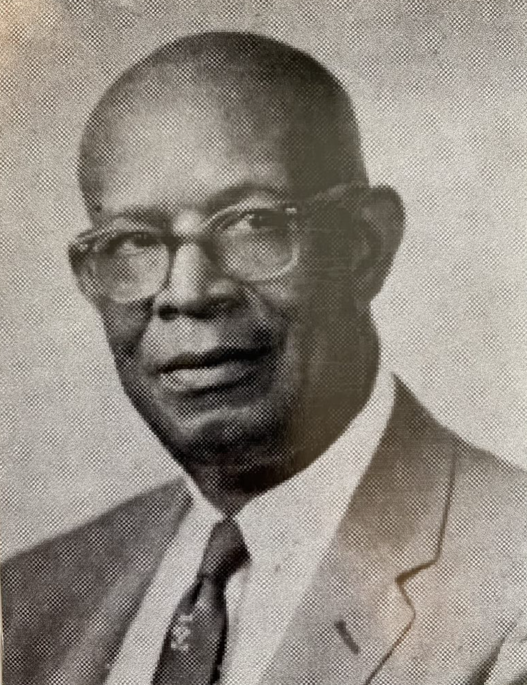 Black-and-white portrait of John McNeile Hunter, who wears glasses and a suit and tie