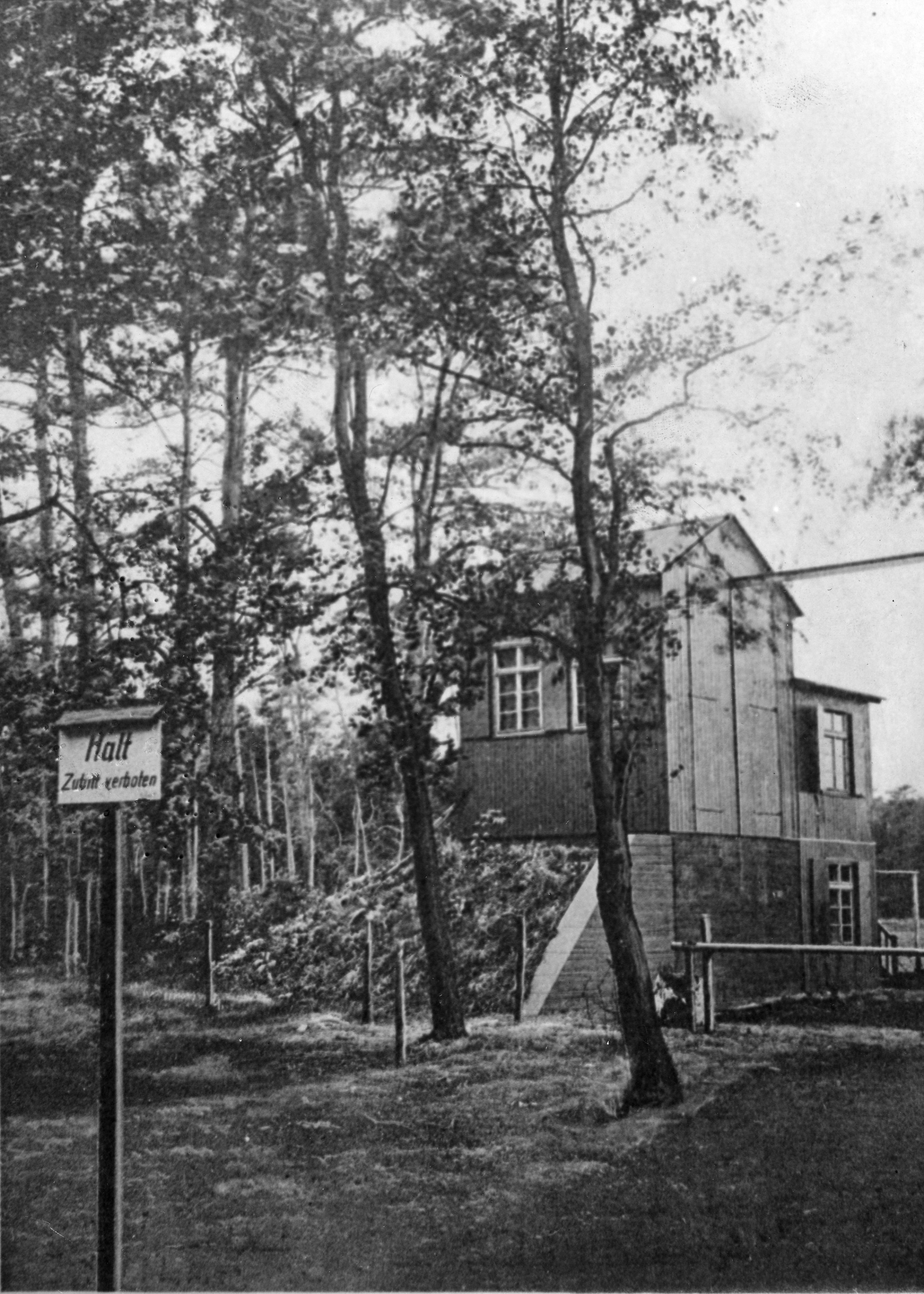 Building in a forest in background. Halt sign in foreground.