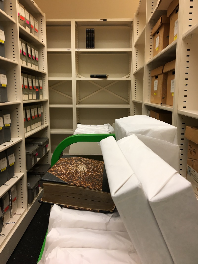 Cart filled with books in the Archives stacks