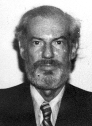 full face black and white photograph of a balding man with a piercing gaze and salt and pepper beard and mustache