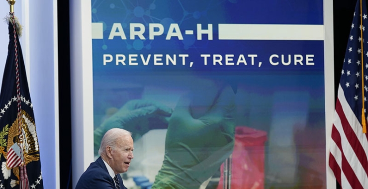 Biden, seated and in profile, in front of a backdrop that reads "ARPA-H: Prevent, treat, cure"