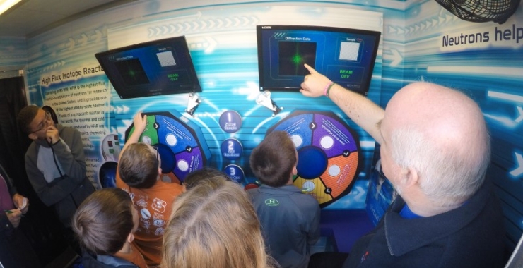 ORNL scientists and children look at a science display