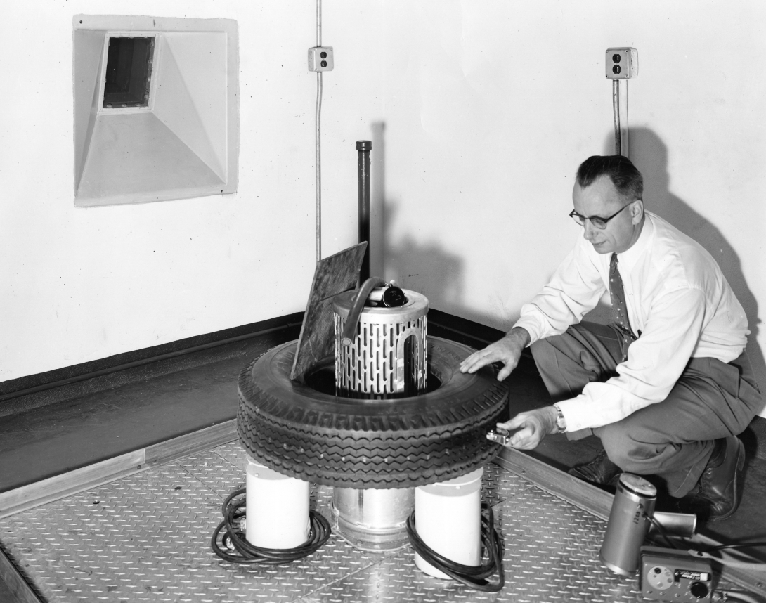 a man bends over a round piece of equipment inside and surrounding a tire