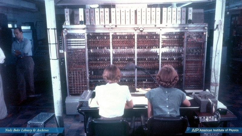 Two women sitting at a computer, seen from the back