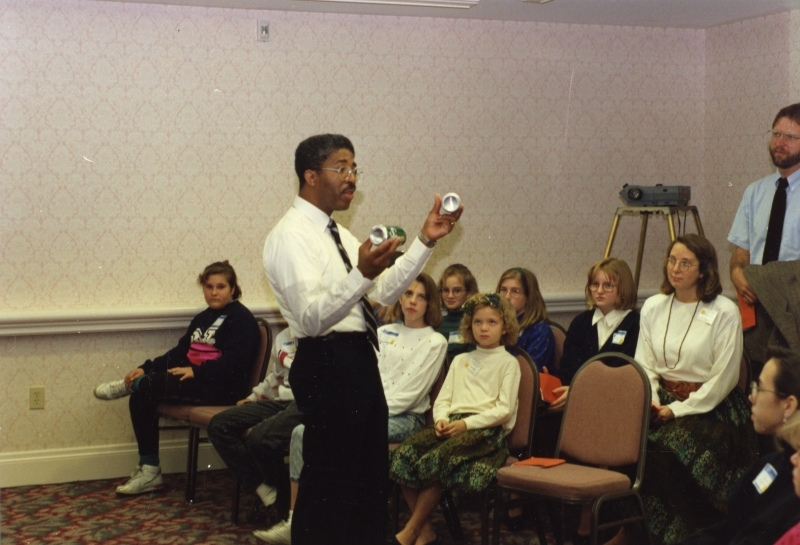 James Stith demonstrates to students holding two cans